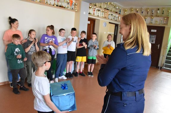 Policjantka wręcza nagrodę uczniowi za zajęcie II miejsca w konkursie fotograficznym.