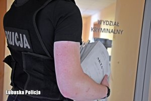 Policjant trzyma w ręce akta sprawy.