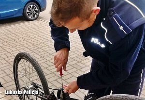 Dzielnicowy pomaga naprawić uszkodzony rower.