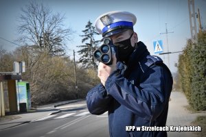 Policjant z miernikiem kontroluje prędkośc kierowców.