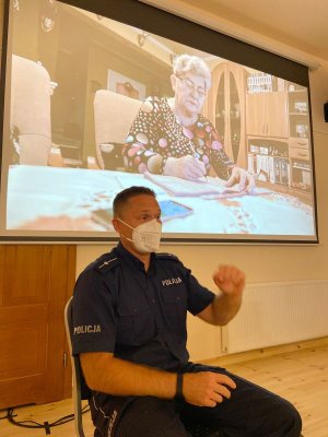 Policjant opowiada seniorom o zagrożeniach związanych z oszustami.