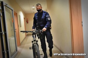 policjant prowadzi odzyskany rower
