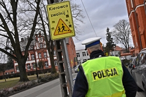 Policjant na tle znaku ostzregawczego o przejściu dla pieszych
