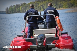 Policjanci na łodzi motorowej płyną po akwenie wodnym