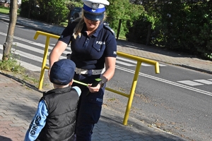 Policjanka przekazuje dziecku odblaski.