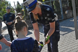 Policjantka przekazuje dziecku odblaski.