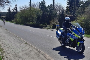 Policjant na motocylku eskortuje kolarza