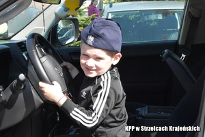 chłopiec w policyjnej czapce siedzi w radiowozie