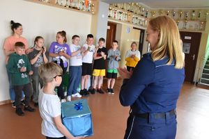 Policjantka wręcza nagrodę uczniowi za zajęcie II miejsca w konkursie fotograficznym.